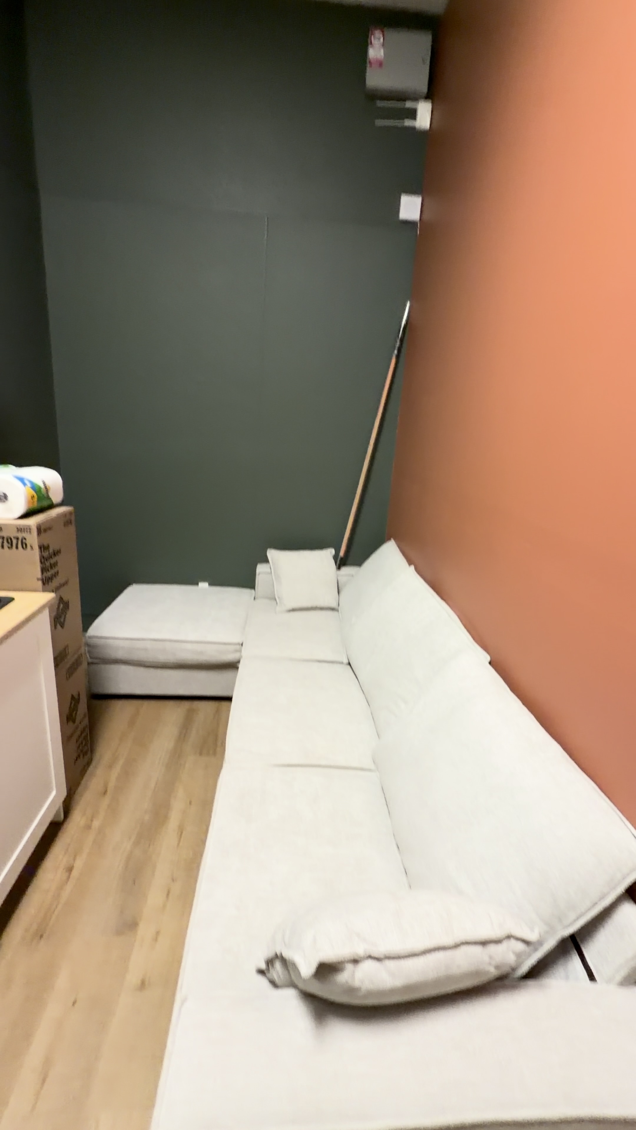 Deep green and orange painted walls behind a light-colored sofa