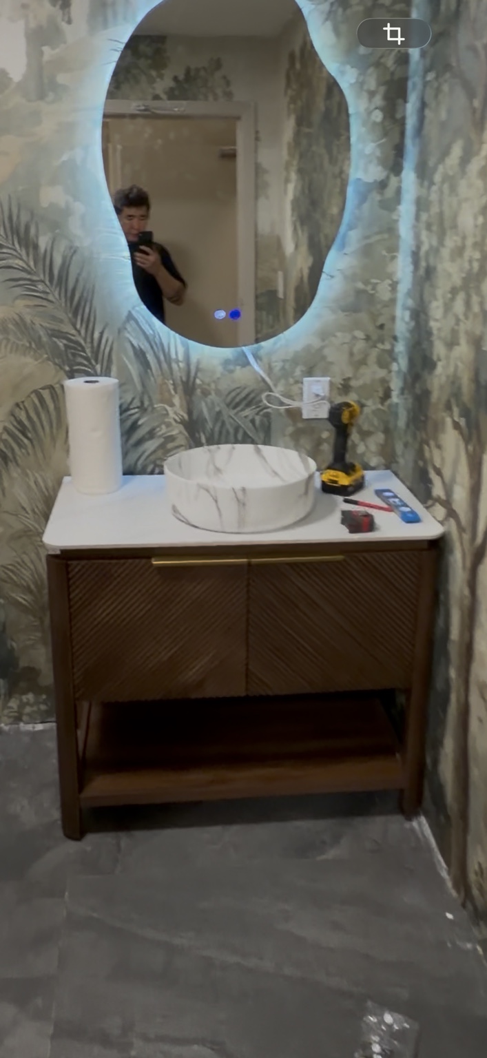 Bathroom vanity with vessel sink and illuminated mirror during work
